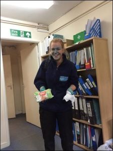 staff member with blue face holding wet wipes