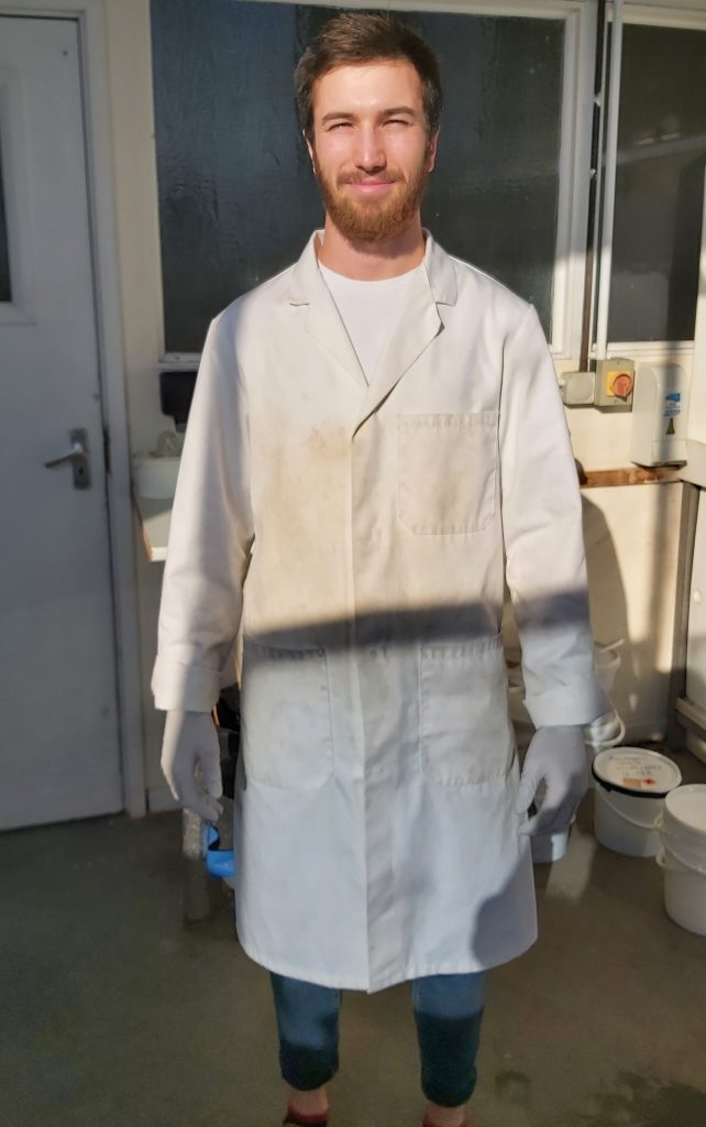 Aston Lockwood in the APEM Marine Biolabs wearing a lab coat and gloves