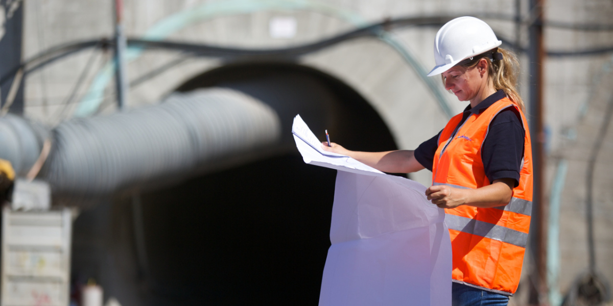 Environmental engineering consultant reviewing technical plans at infrastructure site in Italy, supporting permitting, remediation and sustainability projects